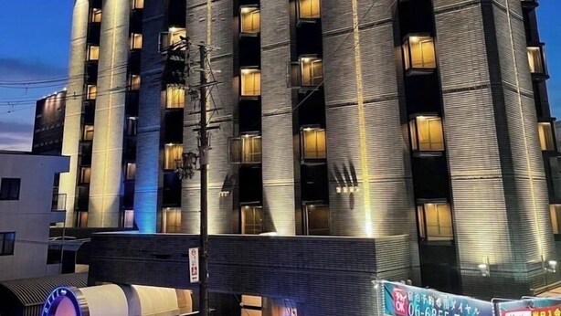 Un hotel de varios pisos con un diseño moderno, que destaca un letrero grande en la parte superior y numerosas ventanas iluminadas.
