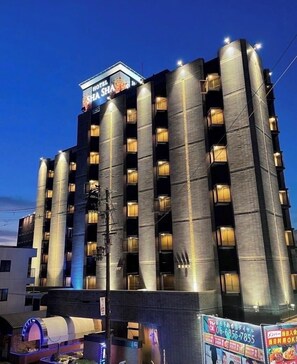 A multi-story hotel with a modern design, featuring a prominent sign at the top and multiple illuminated windows. - Hotel Shasha Toyonaka - Adult Only (Toyonaka)