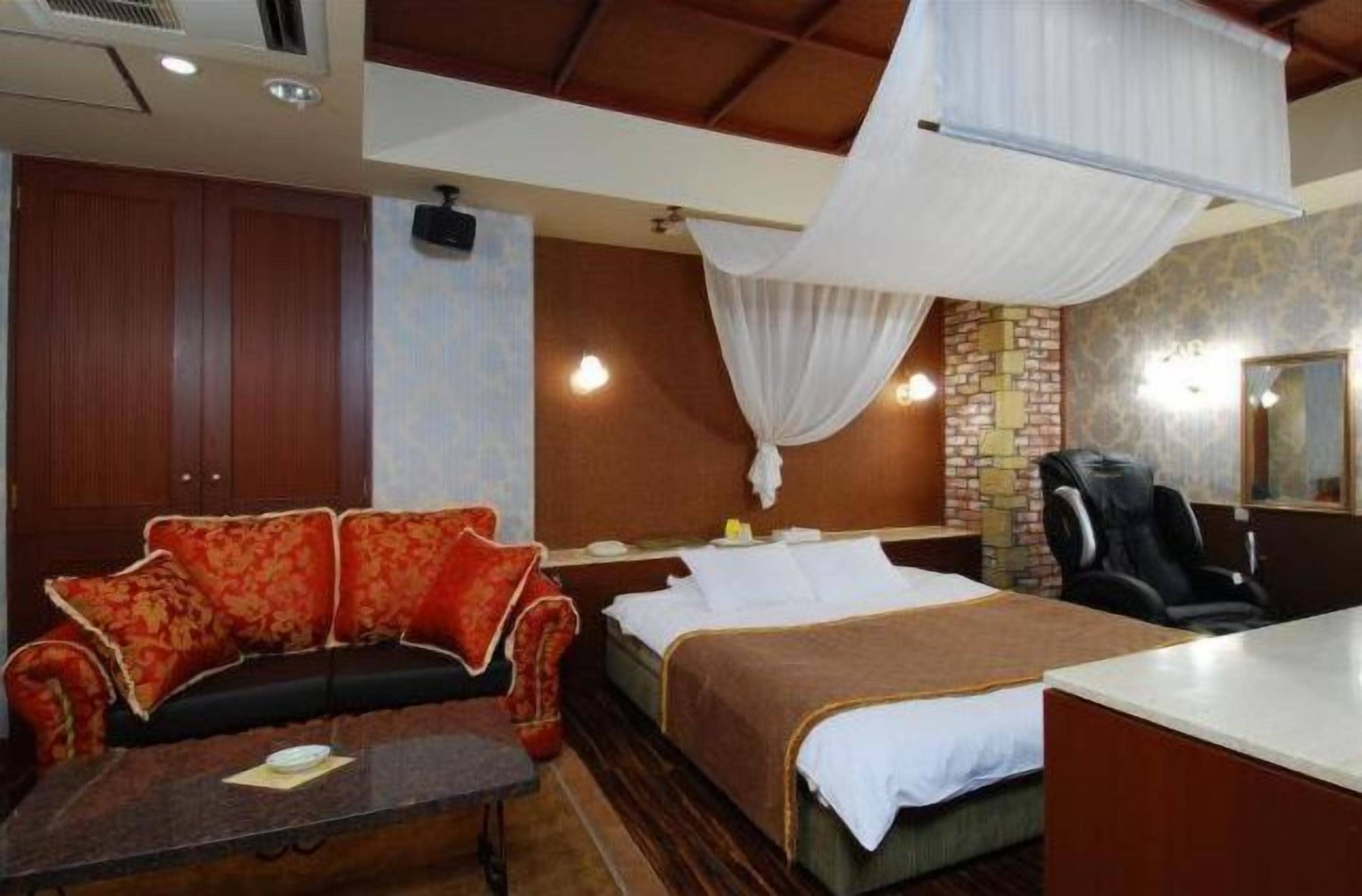 Quarto de hotel com cama, sofá, escrivaninha e cadeira.