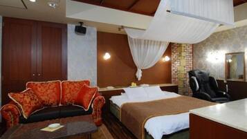 Quarto de hotel com cama, sofá, escrivaninha e cadeira.