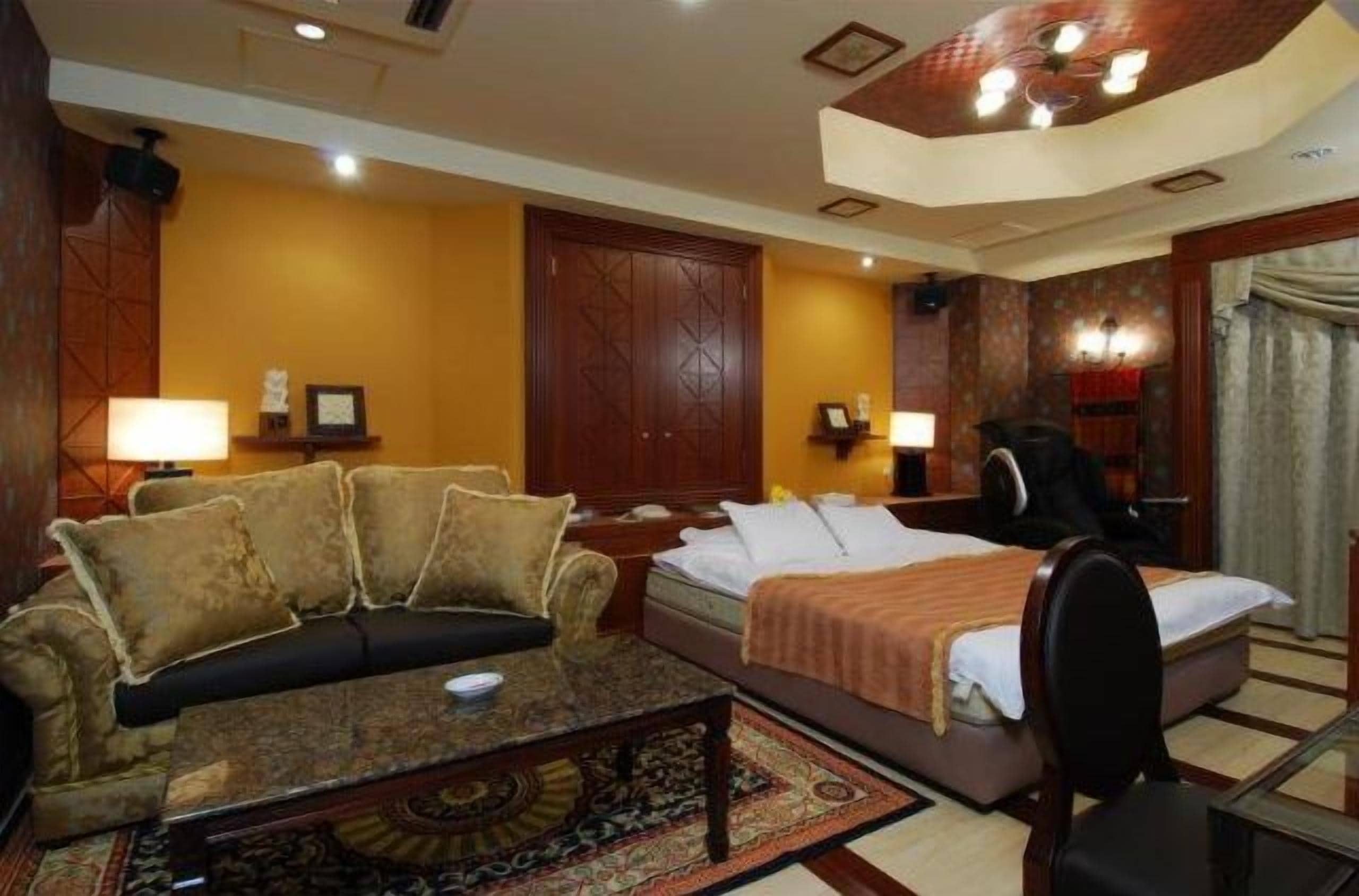 A hotel room with a bed, a sofa, a desk, and a chair.