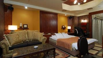 A hotel room with a bed, a sofa, a desk, and a chair.