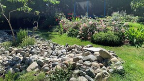 Un jardín con diversas plantas, un ave y una formación rocosa.