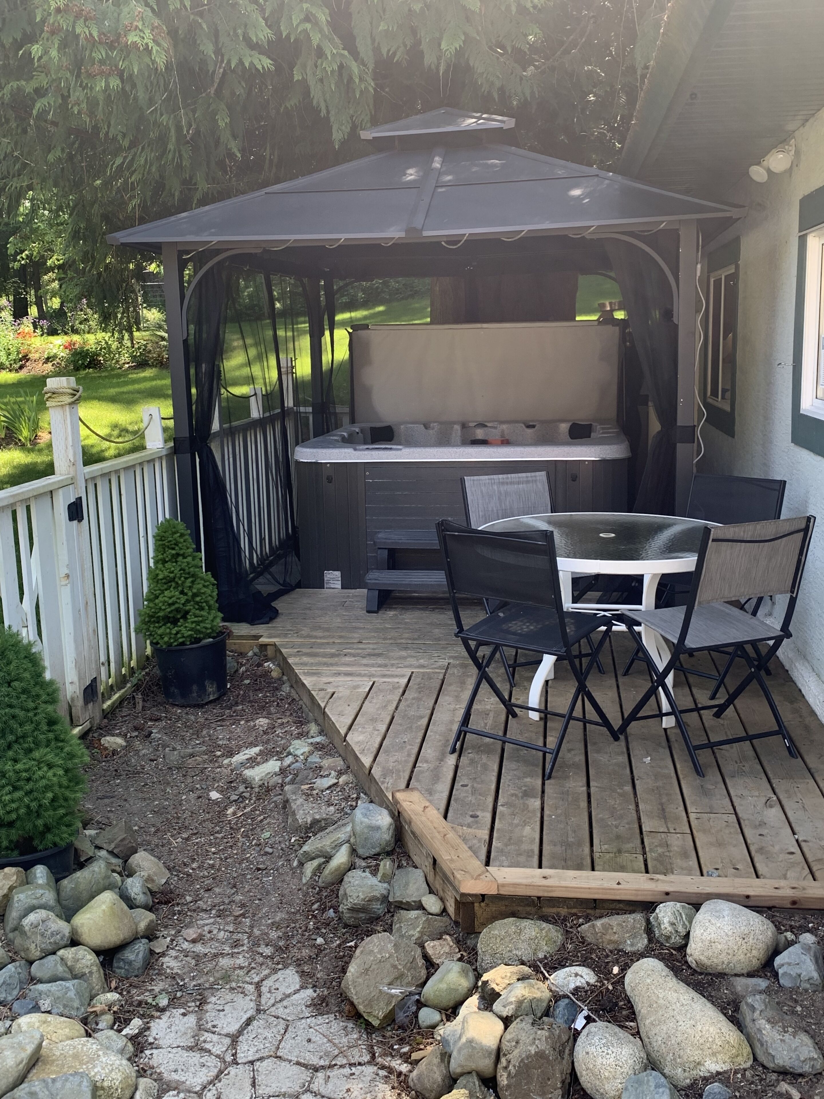 En overdækket terrasse med jacuzzi, træterrasse og udendørs siddeområde.