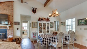 A dining area with a checkered tablecloth, white chairs, a chandelier, and a bear head mounted on the wall. - Nantahala Lake Family Home w/ Private Dock & Views (Topton)