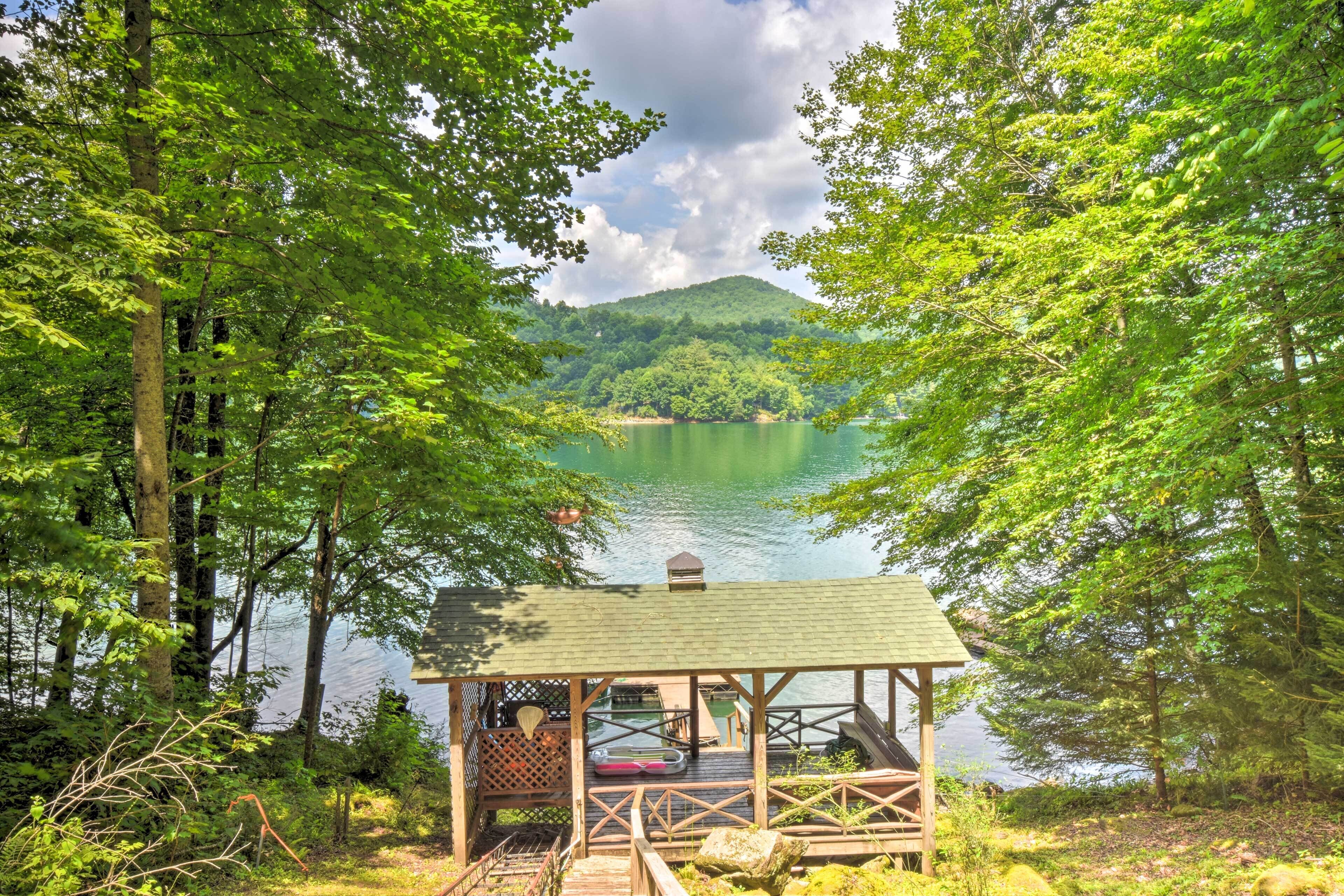 A wooden dock with a gazebo overlooking a lake, surrounded by dense forest.