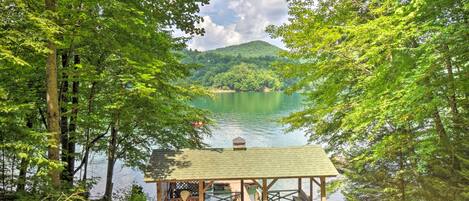 A wooden dock with a gazebo overlooking a lake, surrounded by dense forest.