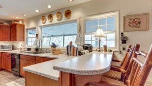 A kitchen with wooden cabinets, a granite countertop, and a large window. - Nantahala Lake Family Home w/ Private Dock & Views (Topton)
