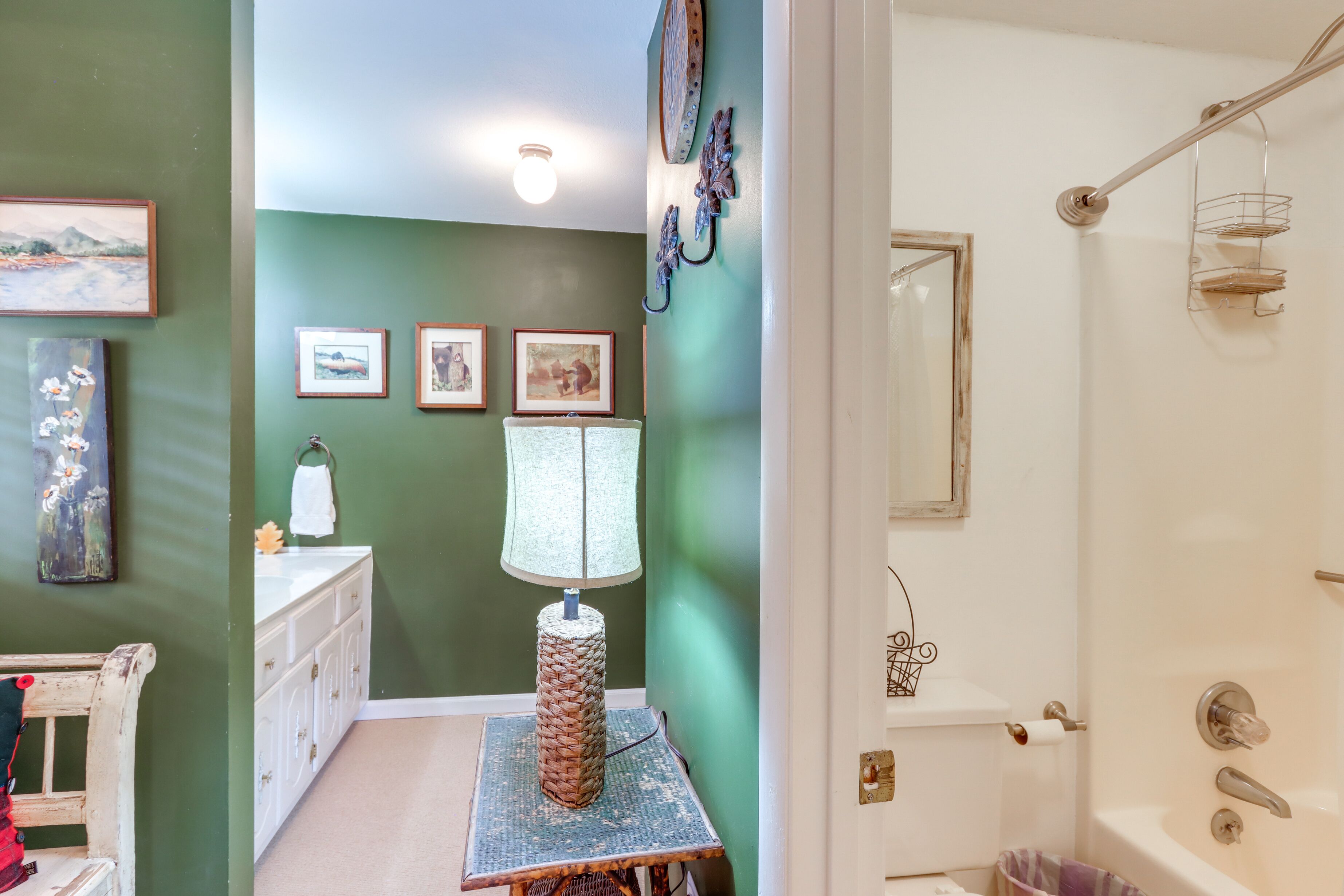 Ein Badezimmer mit Badewanne, Waschbecken und Toilette. An der Wand hängen Bilder in Rahmen und es gibt einen Handtuchhalter.