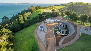 A coastal property with multiple buildings, a winding driveway, and a view of the sea.
