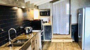 A modern kitchen with a black tiled backsplash, wooden cabinets, a built-in microwave, and a stainless steel refrigerator.