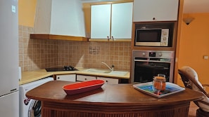 Eine kleine Küche mit Mikrowelle, Backofen und Waschmaschine.
