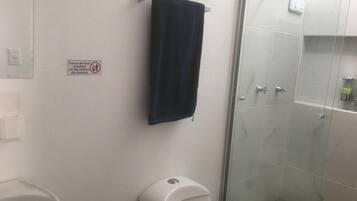 A bathroom with a toilet, a towel hanging on a rack, and a shower area.