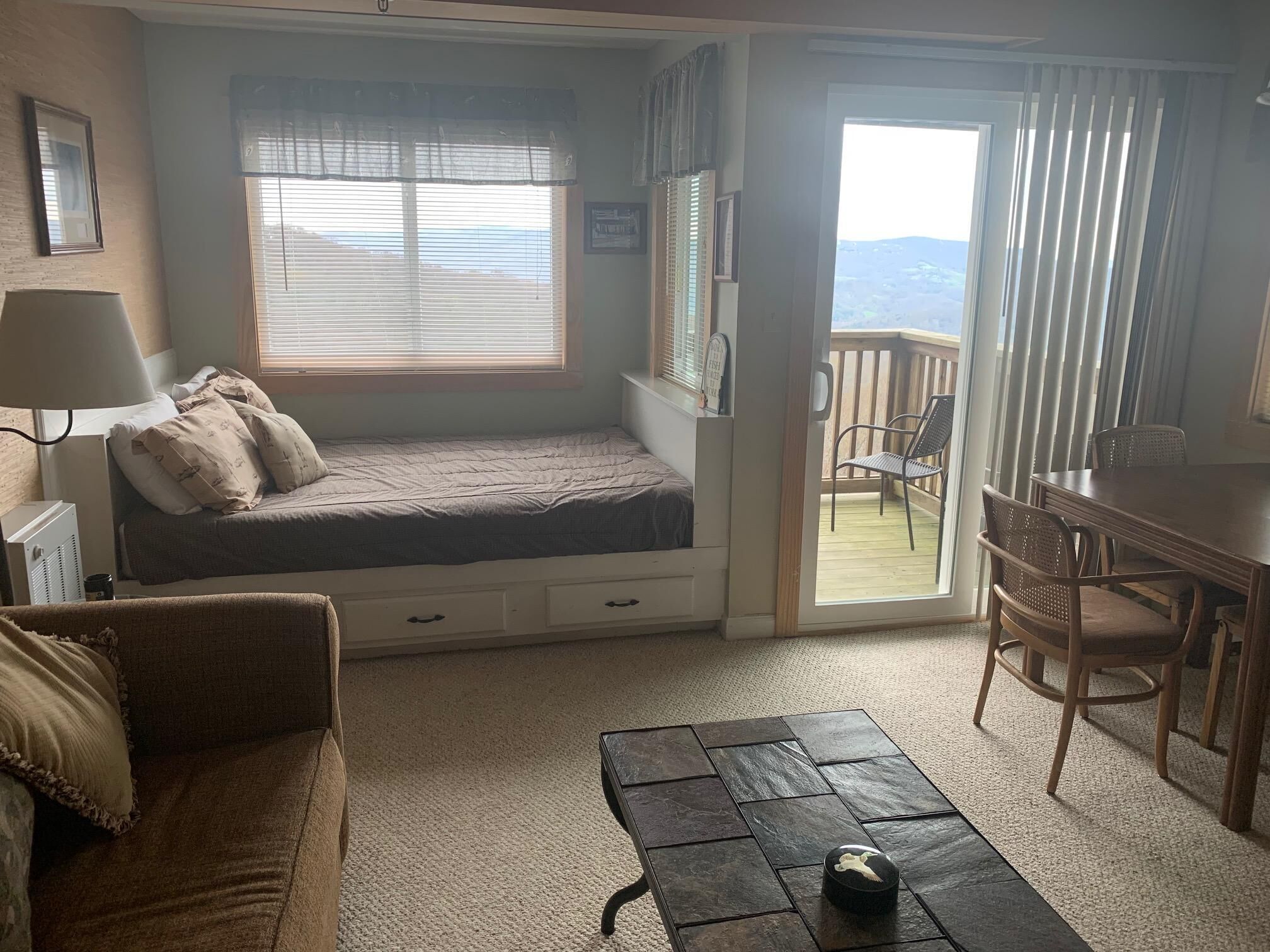A cozy room with a bed, a desk, and a balcony.
