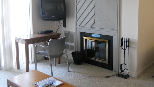 Ein Hotelzimmer mit Fernseher, Kamin, Esstisch und Stuhl.