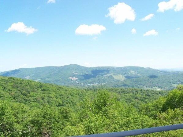 A view of a mountainous landscape with dense green forests and a clear blue sky.