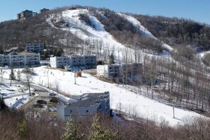A residential area with apartment buildings on a hillside, surrounded by snow-covered ground and trees. - Sugar Ski & Country Club Unit 11-601 Bronze (Banner Elk)