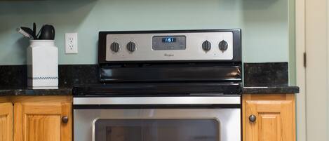 Une cuisine avec des meubles en bois, une cuisinière en acier inoxydable et un plan de travail noir.