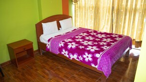A bed with a floral bedspread, a wooden headboard, and a nightstand. - Hospedaje el Oficial (Cusco)