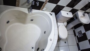 A bathroom with a large bathtub, a toilet, and a bidet. - Hospedaje el Oficial (Cusco)