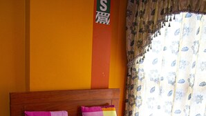 A neatly made bed with a floral bedspread, a wooden headboard, and a pillow with a striped pattern. - Hospedaje el Oficial (Cusco)