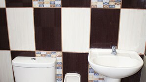 A bathroom with a toilet, sink, and blue trash bin. - Hospedaje el Oficial (Cusco)