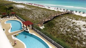 A beach resort with a pool area, a pier in the background, and a sandy beach with umbrellas. - Pearl 704 Sugar White Sand and Emerald Waters. Spectacular view (Navarre)