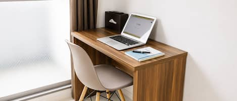 A modern workspace with a laptop, a notepad, and a pen on a wooden desk, a chair, and a window with curtains.