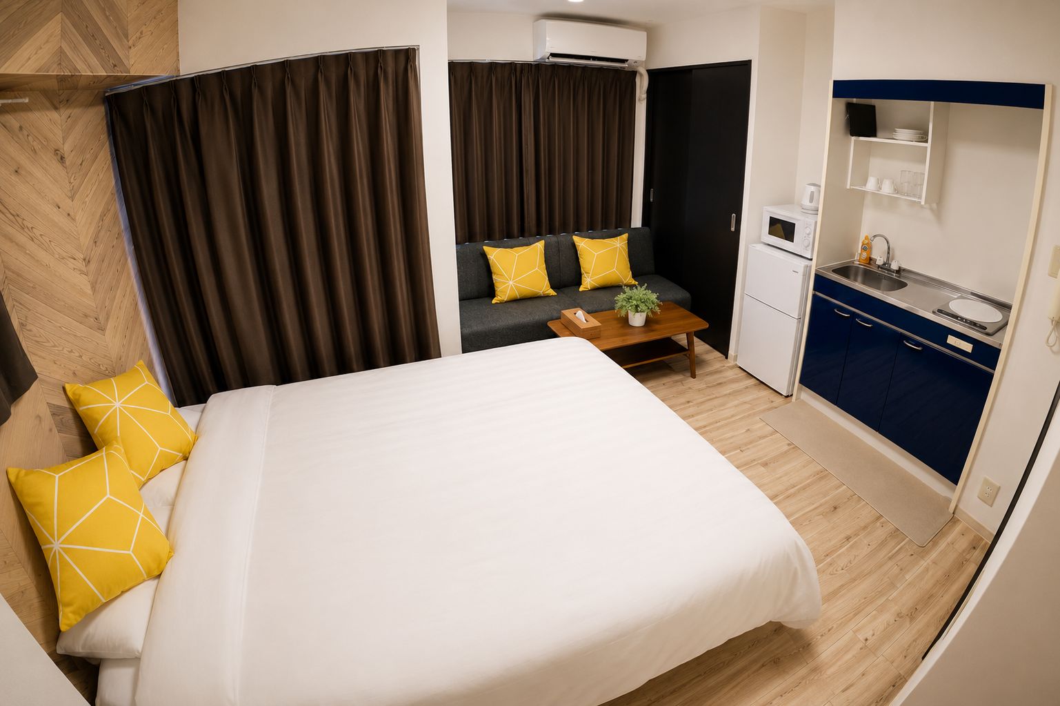 Une chambre d’hôtel comprenant un lit, un canapé, une petite table, une kitchenette et une salle de bain.