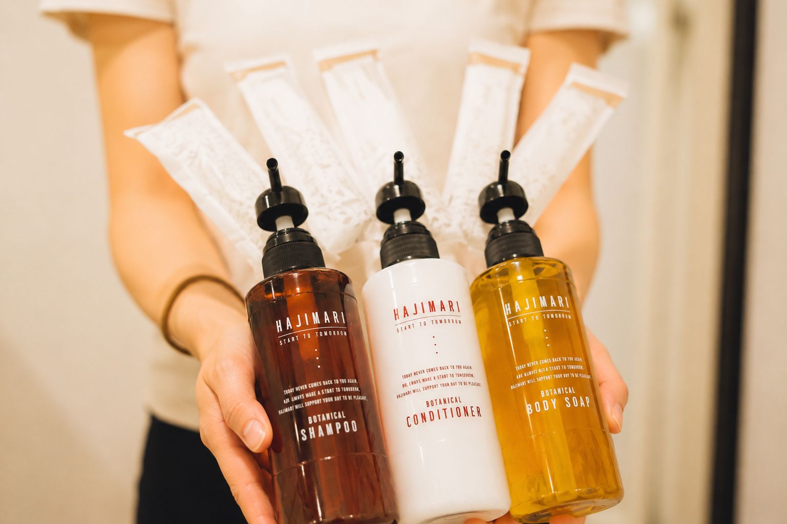 A person holding three bottles of Hajimari body care products.