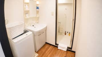 Een compacte badkamer met een wasmachine, een wastafel en een douchecabine.