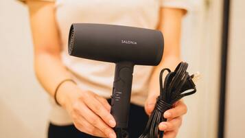 A person holding a black hairdryer with a cord, labeled 'SALONIA.'
