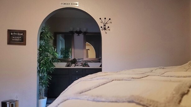 Ein Schlafzimmer mit einem großen Bett, einem Schild für die Toilette, einem Spiegel und einer Zimmerpflanze.