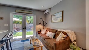 Ett vardagsrum med en brun lädersoffa, ett soffbord och en dörr som leder ut till en uteplats.