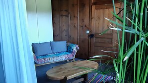 A wooden cabin interior with a sofa, a bench, and a patterned rug.