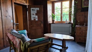 A cozy cabin-style room with a wooden bed, a small table, and a window with a view of greenery.