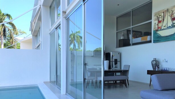 Ein modernes Wohnzimmer mit Glaswand, Pool und Essbereich mit Tisch und Stühlen.