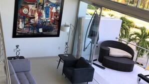 Ein modernes Wohnzimmer mit einem grauen Ecksofa, einem schwarzen Sessel und einem großen abstrakten Gemälde an der Wand.