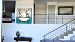 Ein modernes Wohnzimmer mit einem grauen Sofa, einem dunklen Holzkonsolentisch und einem Gemälde eines Segelboots.