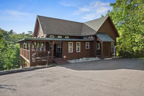 Une cabane en rondins avec un porche, une terrasse couverte et une allée.