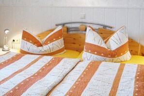 Sänky, jossa on raidallinen vuodevaatesetti ja kaksi tyynyä, joissa on pistekuvio.