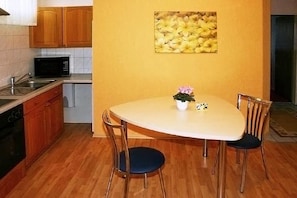 Una cocina pequeña con armarios de madera, microondas, lavabo y una mesa de comedor con sillas.