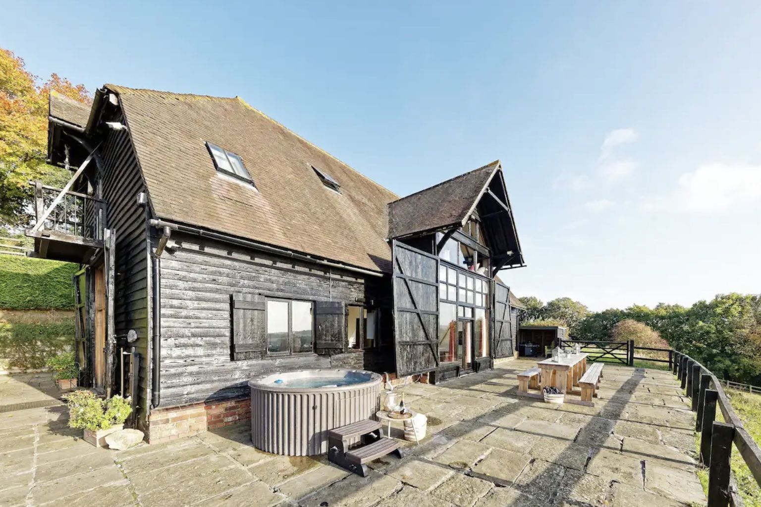 A rustic wooden building with a hot tub and outdoor seating area.