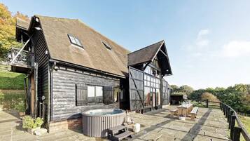 A rustic wooden building with a hot tub and outdoor seating area.