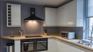A modern kitchen with white cabinets, a black range hood, a microwave, and a sink. - Customs House by Bloom Stays,  Large house for family groups of up to 20 (Faversham)