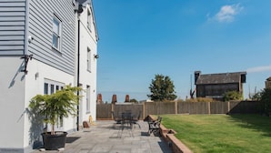 A residential backyard with a patio, a potted plant, and a wooden fence. - Customs House by Bloom Stays,  Large house for family groups of up to 20 (Faversham)