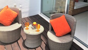 A balcony with wicker furniture, two orange cushions, and two glasses with a candle. - ☺ PUNTAGAVIOTA ☺ HUATULCO ☺ ARROCITO BEACH ☺ (Santa Cruz Huatulco)