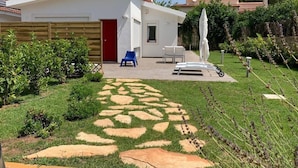 A modern house with a red door, a patio with a white umbrella, and a garden with a stone pathway. - Villa by the sea - in full relaxation - Air conditioned - Wi-fi (Fontane Bianche)