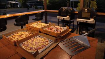 Trois boîtes à pizza sont posées sur une table, avec un coupe-pizza à côté.