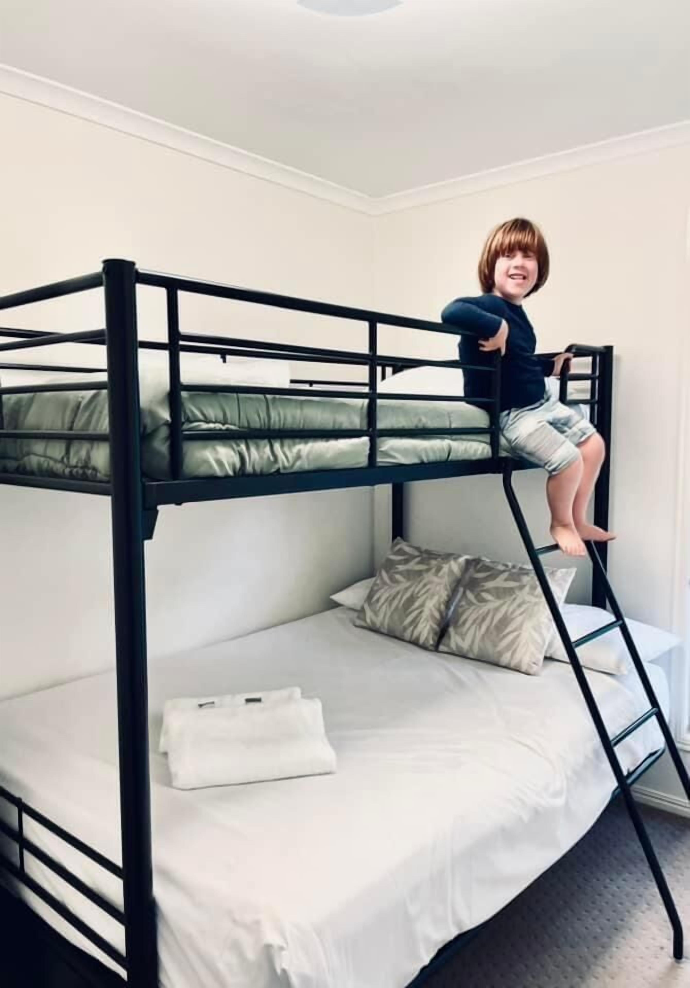 A bunk bed with a child sitting on the top bunk.